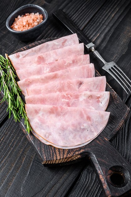 Sliced prosciutto ham on wooden cutting board