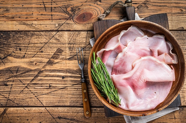 Sliced Prosciutto ham in a wooden plate. wooden background. Top view. Copy space.