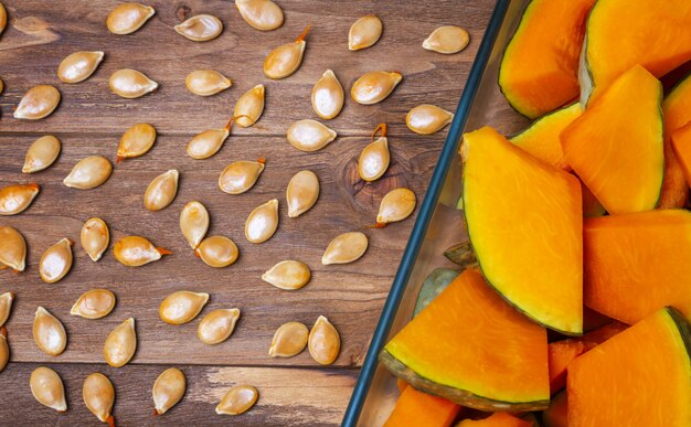 Sliced ​​pumpkin in slices for cooking on a wooden table.