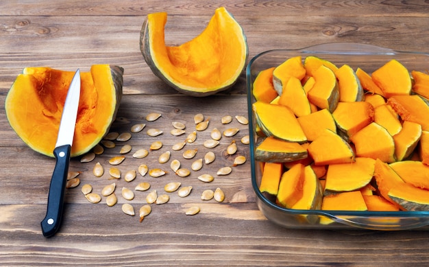 Sliced ​​pumpkin in slices for cooking on a wooden table.