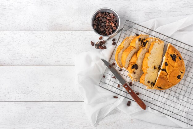 Pane all'uvetta affettato sulla tavola di legno bianca