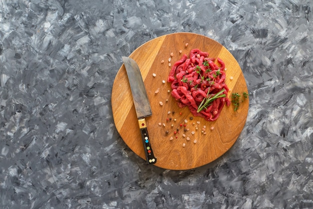 Carne cruda affettata su un bordo di legno. preparazione di manzo alla stroganoff.