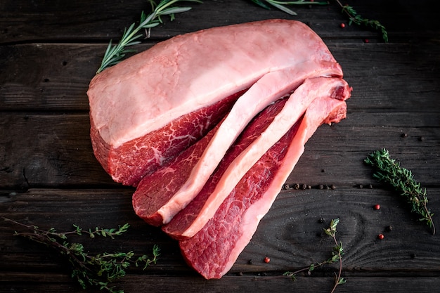 Sliced raw piece of marble beef brisket on wooden background, top view