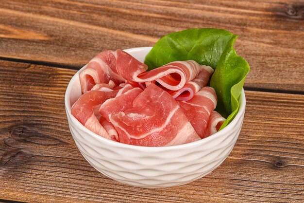 sliced raw pork bacon in the bowl