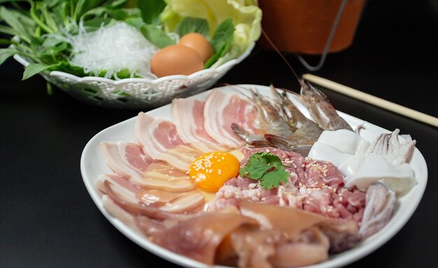 Нарезанная сырая свинина, свежие куриные яйца и свежие овощи исаан тайская еда «чим чам» - известное тайское блюдо с острым соусом для макания.
