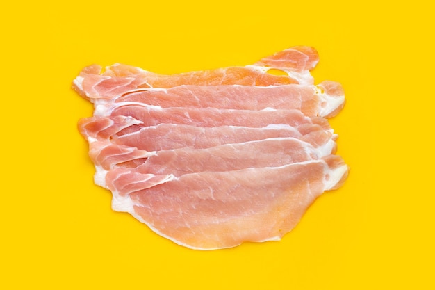 Sliced raw pork meat on yellow background.