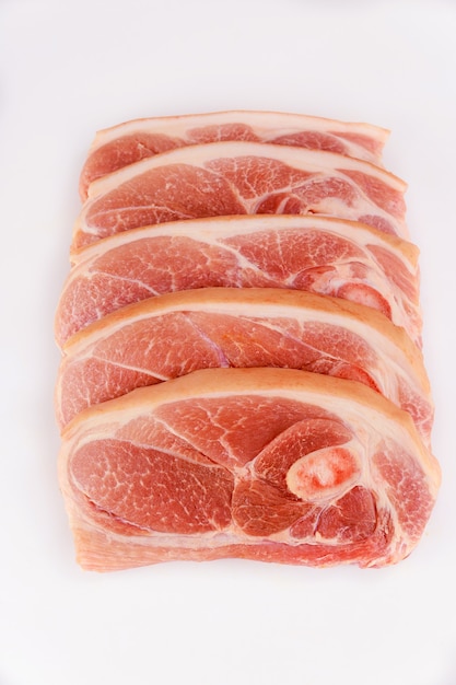 Sliced raw pork shoulder with skin on white isolated surface. Top view.