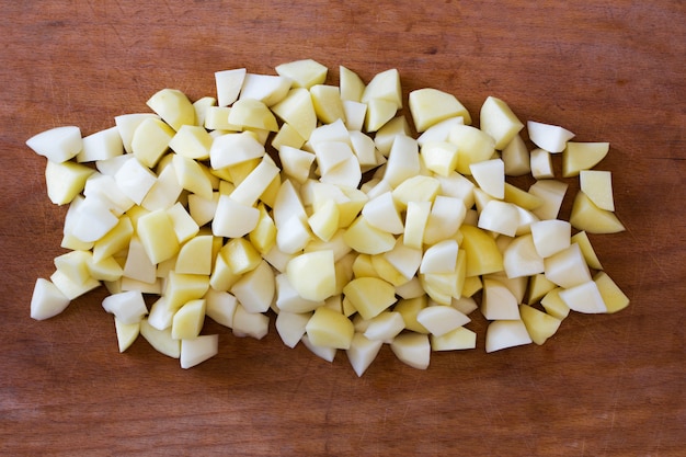 Sliced raw potatoes on a old cutting Board. 