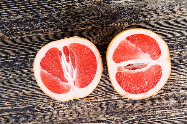 Sliced red grapefruit on a black table, close-up of citrus juicy and delicious