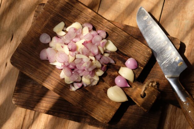 sliced red onion and garlic on a teak wood cutting board. stainless steel blade. spices. Allium cepa