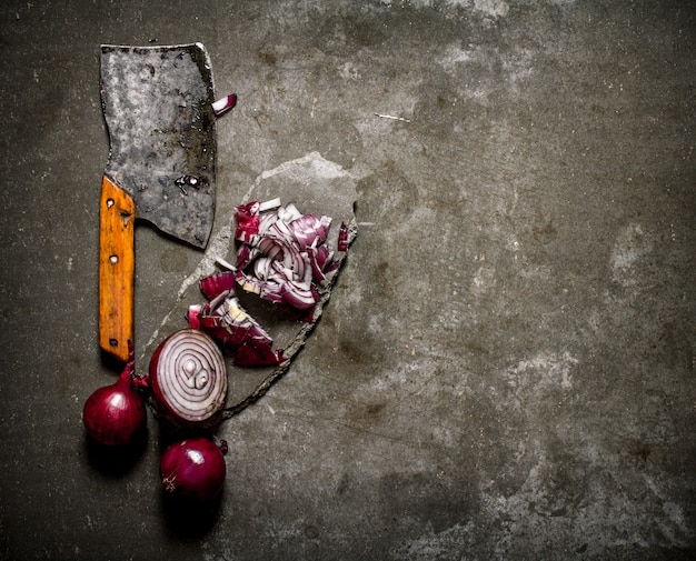 Sliced red onion and an old hatchet on a stone stand on grey table