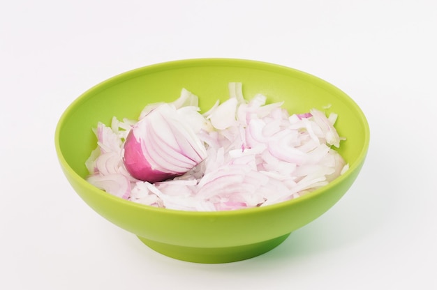 Sliced red onions in a green bowl isolated on a white background