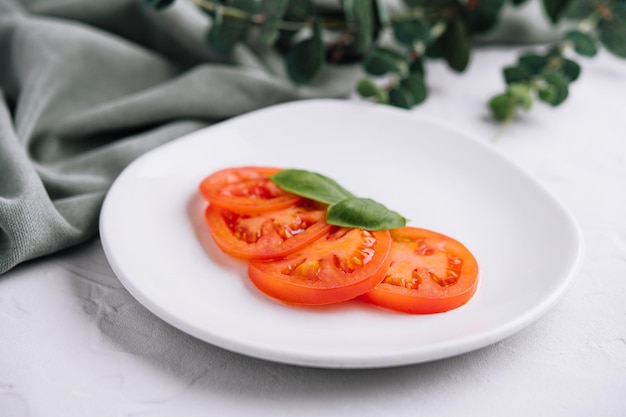 Sliced red tomatoes and basil leaves