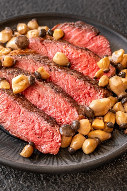 Sliced rib eye steak with mushrooms on the plate