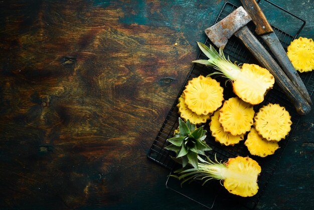 Sliced ripe baby pineapple on a black stone background. Tropical fruits. Top view. Free space for text.