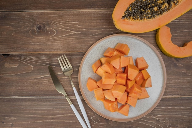 Sliced ripe papaya fruit on white plate with fork ready to eating Tropical fruit Top view