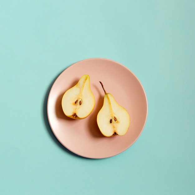 Photo sliced ripe pear on a plate on blue