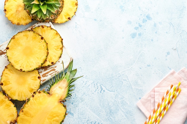 Sliced ripe pineapple on light blue stone background. Tropical fruits. Top view. Free space for text. 