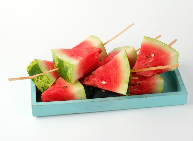 Sliced ripe red watermelon with seeds on a wooden blue board