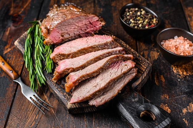 Sliced Roast beef sirloin tri tip steak bbq. Dark wooden background. Top view.