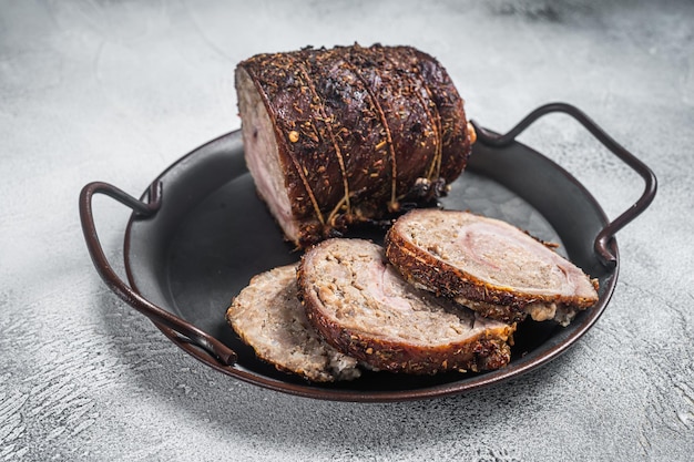 Sliced roast pork meat  roulade on a steel tray White background Top view