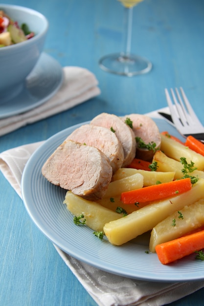 Sliced roast pork tenderloin with potatoes and carrots