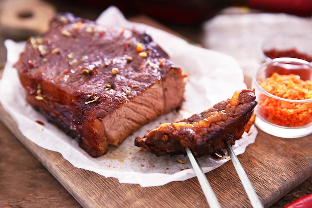 写真 木製の背景に肉フォークとスパイスをスライスしたローストポークステーキ