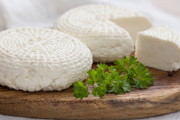 Sliced round white homemade cheese traditional milk creamy dairy product on vintage wooden board