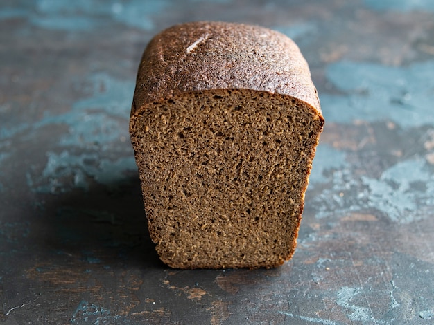 Sliced rye bread on cutting board on dark background. Copy space, close up.