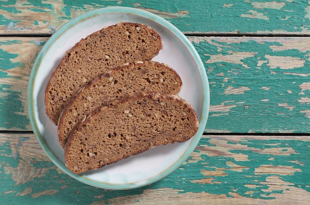 Sliced rye bread in plate on old green wooden background