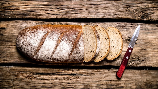 Sliced rye bread with a knife. On a wooden table. Top view