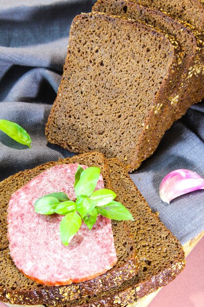 Sliced rye bread with leaf basil on cutting board Whole grain rye bread with seeds