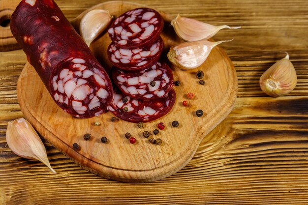 Sliced salami sausage on cutting board on wooden table