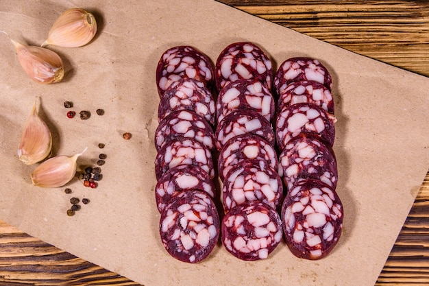 Sliced salami sausage and garlic on a brown wrapping paper Top view