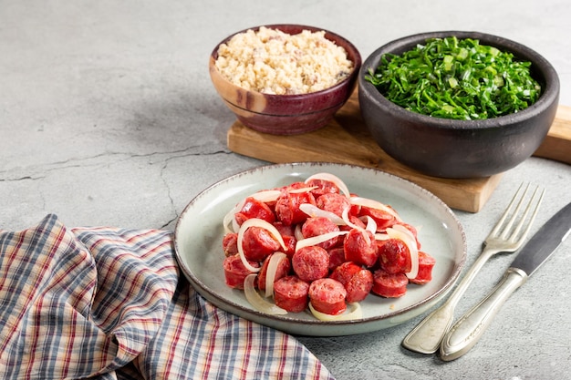 Sliced sausage with onion green cabbage and farofa