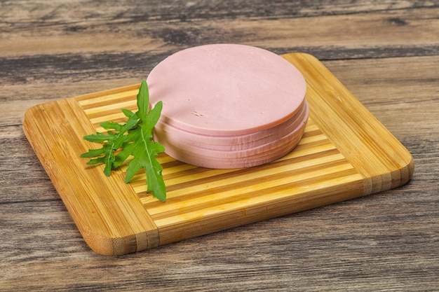 Sliced sausage over the wooden board