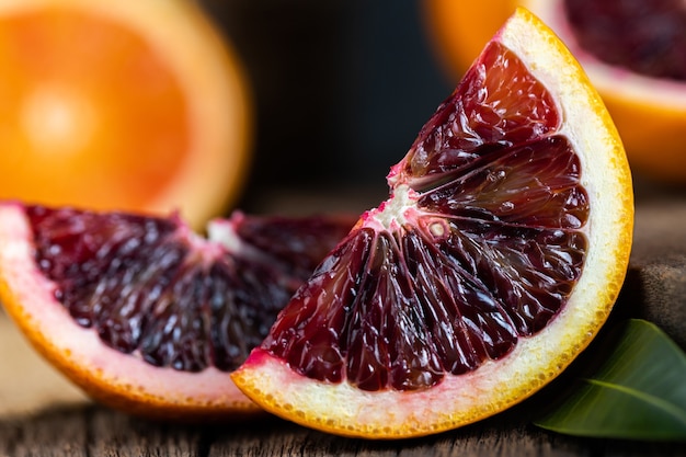 古い暗い木製の背景の上にスライスしたシチリアのブラッドオレンジの果実。