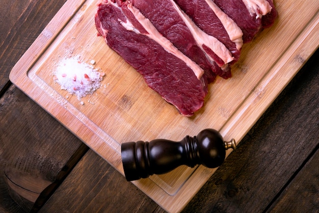 Photo sliced sirloin rosemary salt and pepper moulin on bamboo cutting board