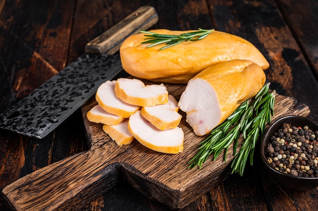 Sliced Smoked chicken breast fillet meat on a butcher board.