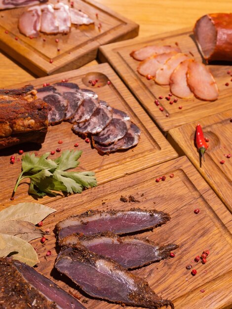 Sliced smoked gammon on a wooden table with addition of fresh herbs and aromatic spices