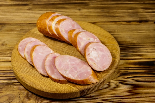 Sliced smoked sausage on cutting board on wooden table