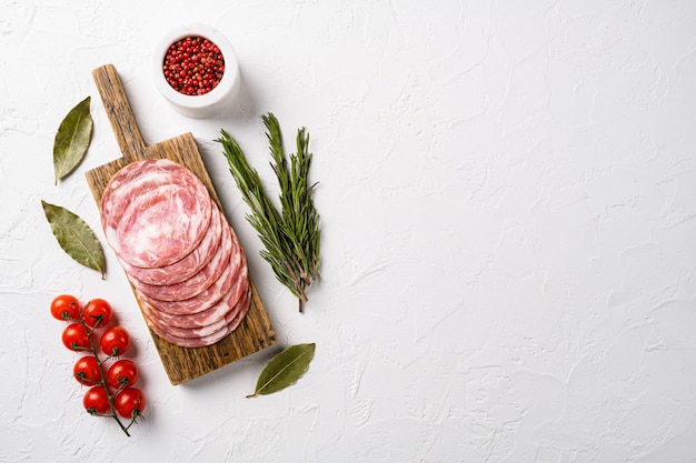 Sliced smoked sausage set, on white stone table background, top view flat lay, with copy space for text