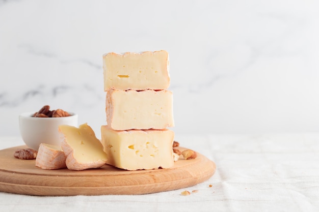 Sliced soft cheese with mold on a wooden board on a white background