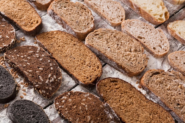 Sliced sorts of bread gradient background. Bakery and grocery concept. Fresh, healthy whole grain sliced sorts of rye and white loaves on wood