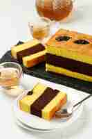 Photo sliced spiku or lapis surabaya indonesian three layer cake with with strawberry jam between the layer topped with prunes on white table