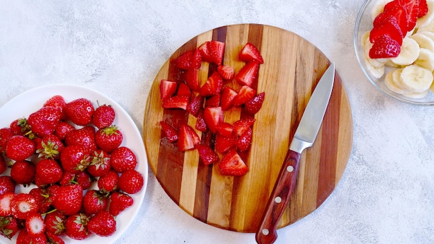 Sliced strawberry on wooden board Preparing smoothie or milkshake with strawberry and banana