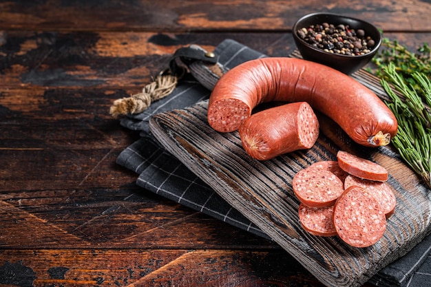 Sliced Sucuk beef meat sausage on a cutting board with herbs Wooden background Top view Copy space