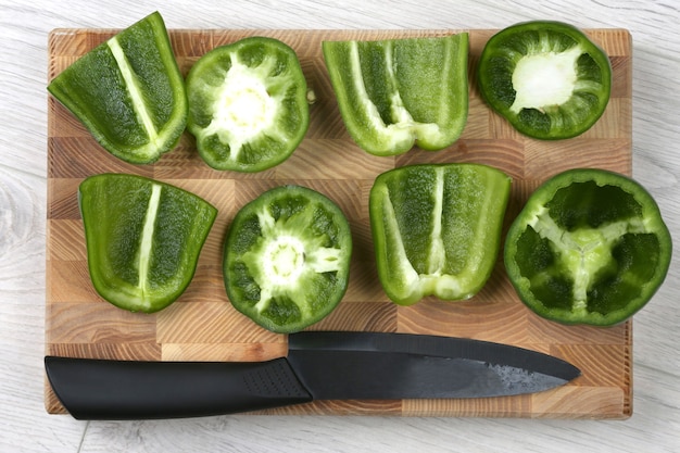 Photo sliced sweet peppers with a ceramic knife on a wooden board. raw food for cooking
