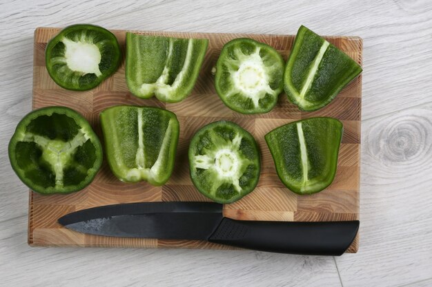 Sliced sweet peppers with a ceramic knife on a wooden board