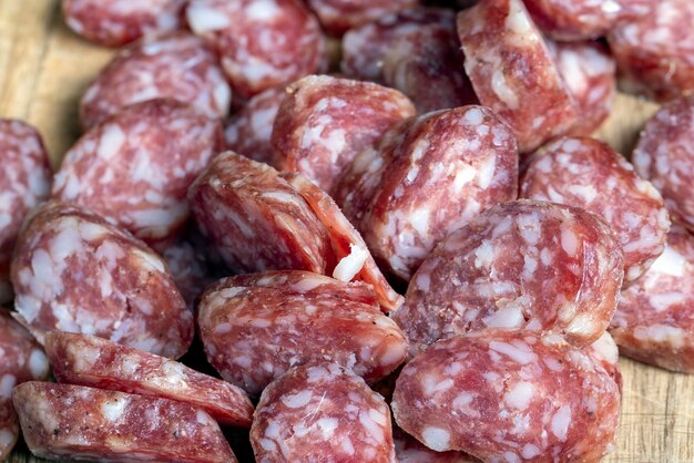 Sliced thin sausage with bacon on a wooden dish